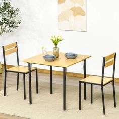 two chairs and a table with flowers in vases on it near a wall mounted plant