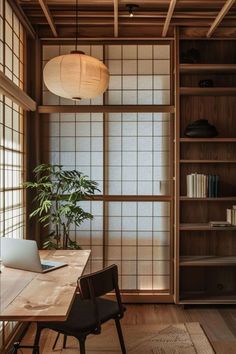 a wooden table with a laptop on top of it next to a book shelf and window