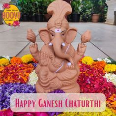 an elephant statue sitting in the middle of flowers with happy ganesh chaturtti written on it