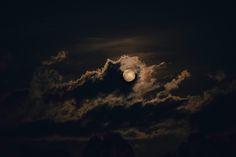 the full moon is shining brightly in the dark night sky with clouds and trees around it