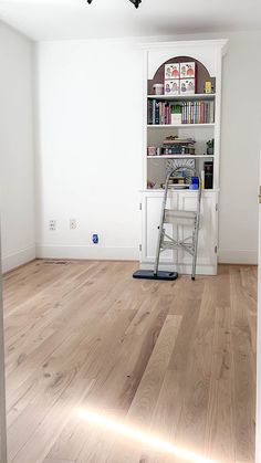 an empty room with a ladder and bookshelf in the corner next to it