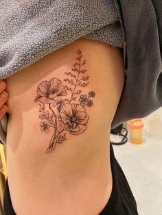 a woman's lower back tattoo with flowers on her stomach and the bottom part of her body