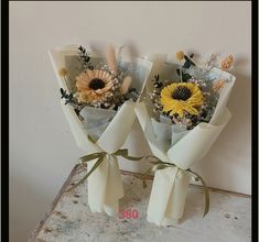 two bouquets of flowers are wrapped in white paper