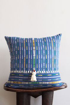 a blue and white pillow sitting on top of a wooden table