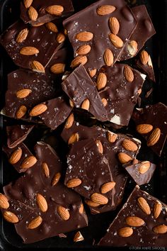 chocolate and almonds are arranged on top of each other in a black tray,