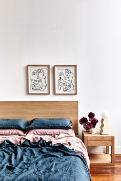 a bed with two paintings above it and a nightstand next to it in a bedroom