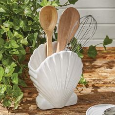 two wooden spoons in a shell shaped holder with whisk utensils