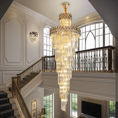 a large chandelier hanging from the ceiling in a room with stairs and windows