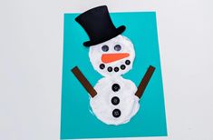 a snowman made out of icing and buttons on a blue paper plate with a black top hat