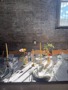 the table is set with plates and silverware, flowers in vases, and candles