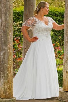 a woman in a white dress standing under some wooden pillars