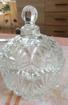 a clear glass bottle sitting on top of a white tablecloth covered table next to a dresser