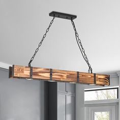 a wooden light fixture hanging from the ceiling in a room with white walls and wood flooring