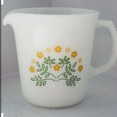 a white pitcher with yellow flowers painted on it