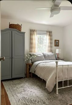 a bedroom with a bed, dresser and rug in the corner next to a window