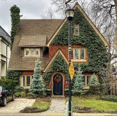 a house with ivy growing all over it's roof and windows, along with a car parked in front