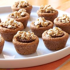 a white plate topped with chocolate cupcakes covered in nuts