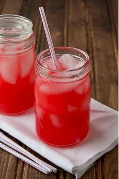 two mason jars filled with watermelon and ice sitting on top of a napkin