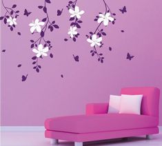 a pink couch in front of a purple wall with white flowers and butterflies on it