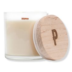 a glass candle with a wooden lid and the letter p on it's side