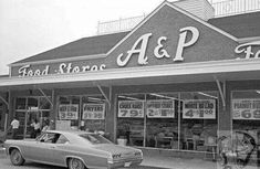 an old black and white photo of a car parked in front of a food store