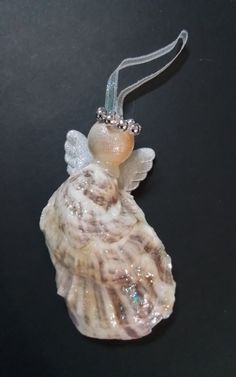 a glass angel ornament hanging from a string on a black surface with beads