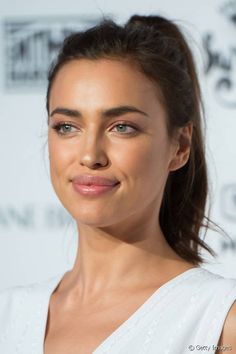 a woman in white dress posing for the camera with her hair pulled back and green eyeshad