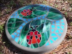 a colorful glass plate sitting on top of the ground next to some grass and dirt