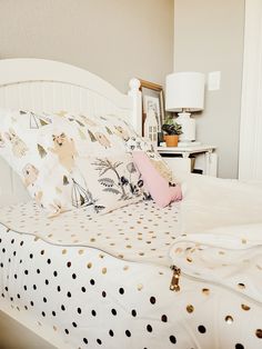 a white bed topped with lots of pillows next to a night stand and table lamp