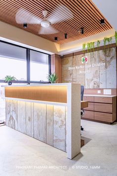 the reception desk is made of marble and has plants hanging from it's ceiling