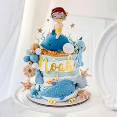 a blue and white cake with a little mermaid on it's top that says noah