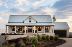 a white house with a metal roof and two car garages on the side of it