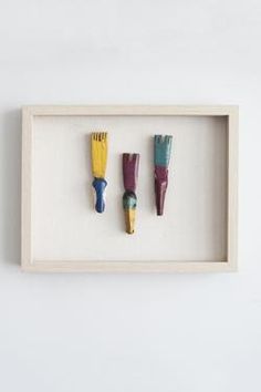 three different colored toothbrushes in a shadow box