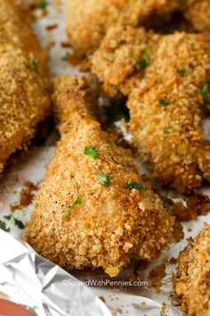 chicken nuggets with parmesan cheese and herbs on top, sitting in foil