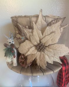 a hat with poinsettis and pine cones is on top of a glass vase