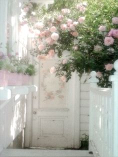 a white door with pink flowers growing over it