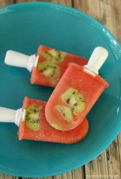 two popsicles with fruit on them sitting on a blue plate