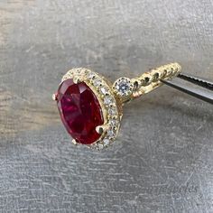 an oval shaped ruby and diamond ring on a metal surface