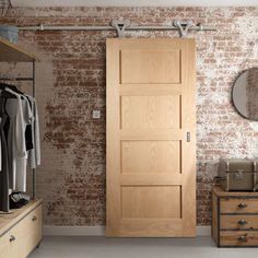 a bedroom with brick wall and wooden closet doors in the corner, open to reveal a walk - in closet