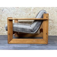 a chair that is made out of wood and has a gray fabric seat pad on it