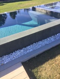 an empty pool in the middle of a grassy area with rocks and gravel around it