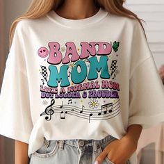 Band Mom Shirt, Band Mama Shirt, Loud And Proud Band Mama Shirt, Trumpet Shirt, Proud Mom Shirt, Band Mom Tee, High School Matching Band Tee ♦ ♦ ♦ ♦ ♦ ♦ ♦ ♦ ♦ ♦ ♦ ♦ ♦ ♦ ♦ ♦ ♦ ♦ 🌸 Material: - Made of 50% cotton and 50% polyester. - Medium-heavy fabric. - True to size. - Unisex design fits like a traditional semi-fitted men's t-shirt but looks great on both men and women. Men should order their usual size or size up for a looser fit. - For detailed sizing and color options, please refer to the li Music-themed White Tops With Letter Print, Custom Print Cotton Tops For Concert, Music-themed White Cotton Top, White Cotton Music-themed Top, White Music-themed Cotton Top, Custom Print Cotton Shirt For Concerts, White Cotton Music-themed Shirt, Music-themed White Relaxed Fit Top, Trumpet Shirts