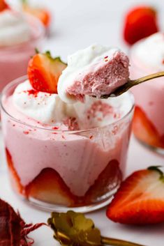 two desserts with strawberries and whipped cream in them on a white table top