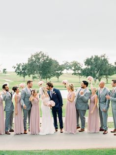 a group of people standing next to each other in front of a field and trees