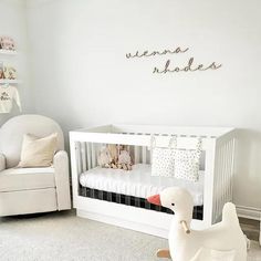 a baby's room with a white crib, rocking chair and stuffed animal