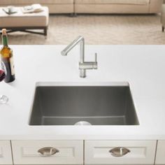 a white counter top with a sink and two glasses of wine on it next to a couch