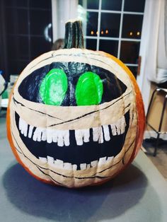 a decorated pumpkin with green eyes and mouth