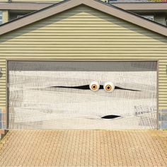 two fake eyes on the side of a garage door in front of a brick driveway