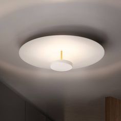 a white ceiling light with a circular design on the ceiling and wooden cabinets in the background