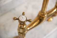 a close up view of a brass clock on a marble table with white and gold accents